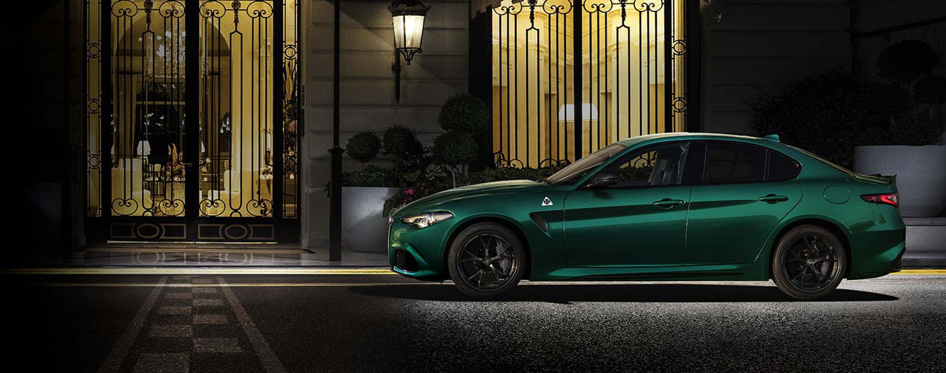 Side profile of a green giulia QV outside a hotel