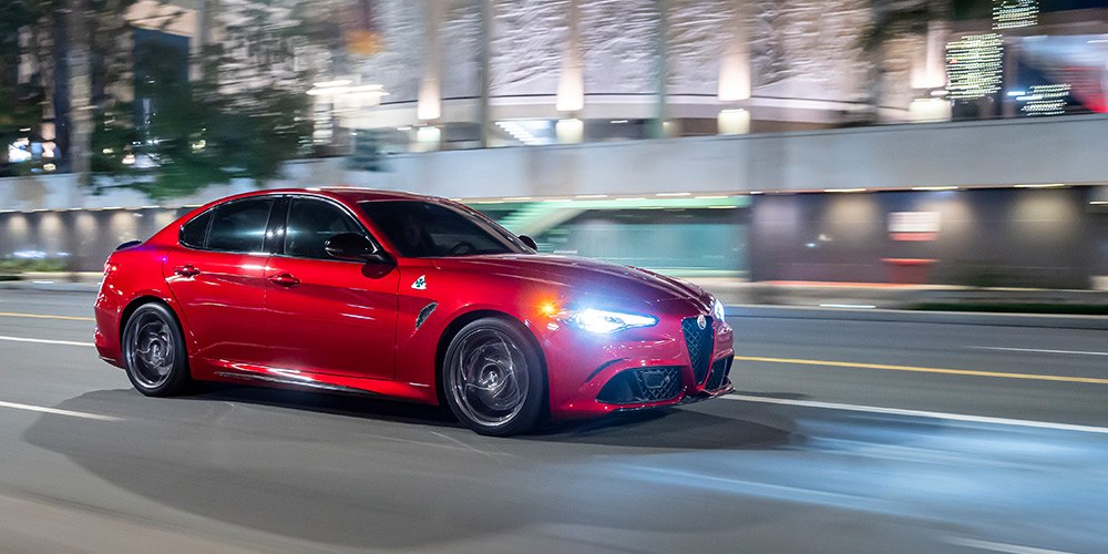 Front 3/4 shot of a Giuliaq QV driving through a city