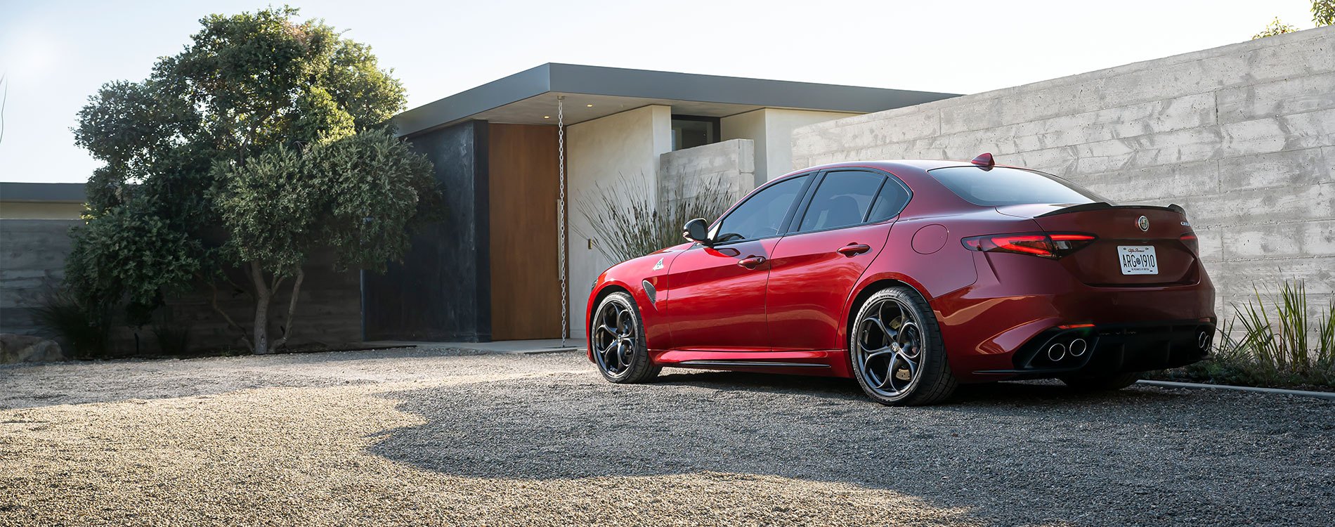 Rear 3/4 shot of a red Giulia QV parked outside