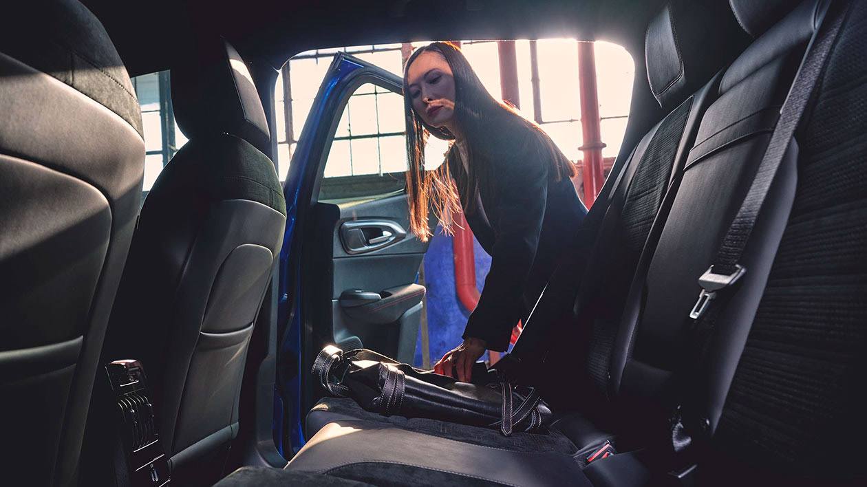 A woman putting luggage on the rear seat of an Alfa Romeo