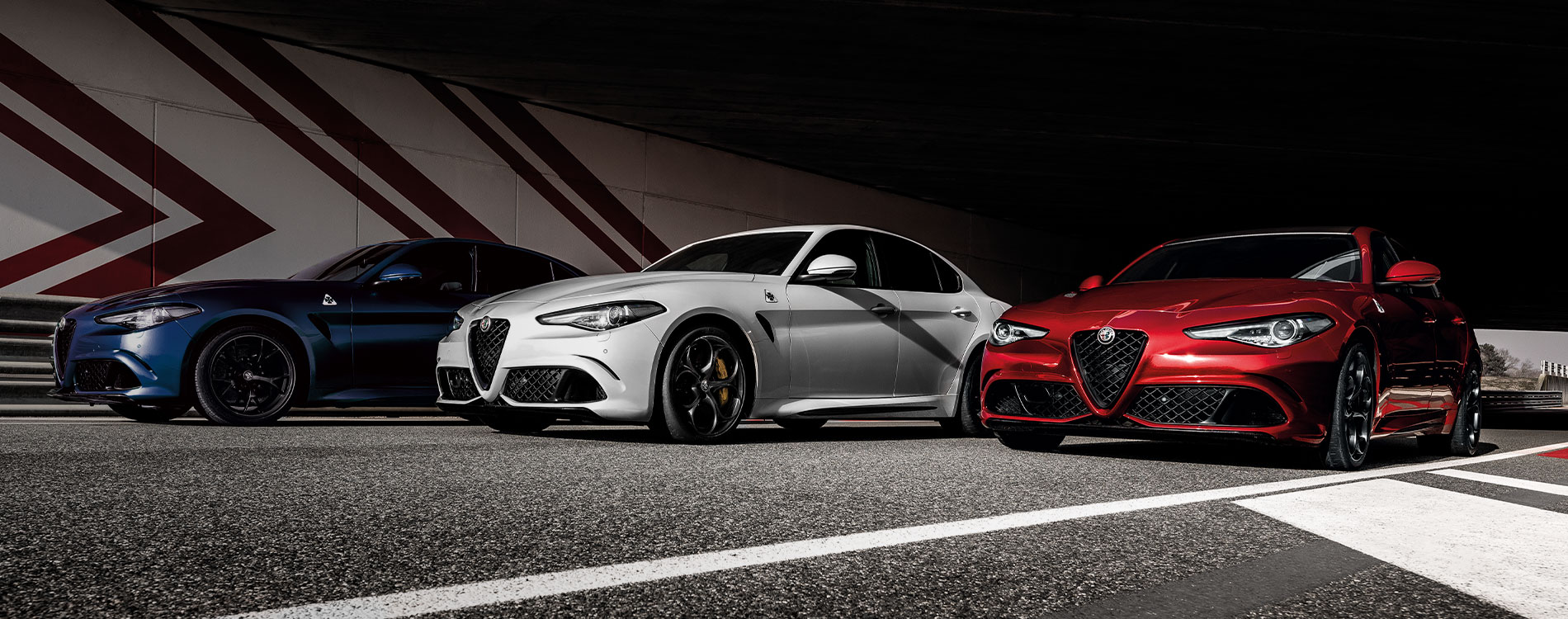 3 alf romeo models in a line by a desert road