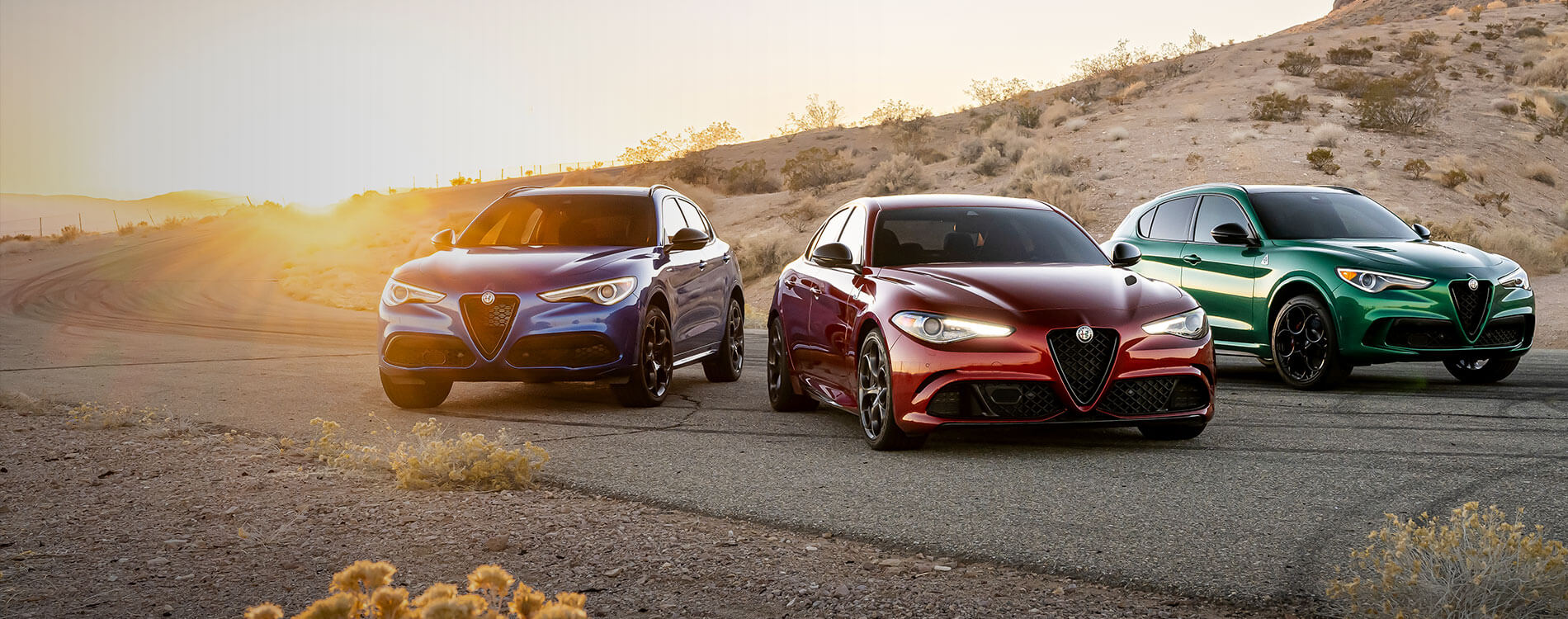 3 alf romeo models in a line by a desert road